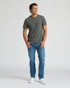 Man wearing a gray t-shirt and blue jeans on a white background