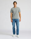 Man wearing a gray t-shirt and blue jeans on a white background