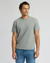 Man wearing a gray t-shirt and blue jeans against a plain background