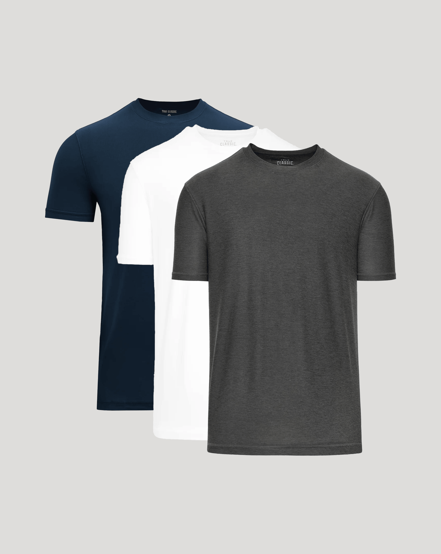 Three plain t-shirts in navy, white, and gray on a light gray background
