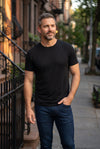 Classic Look - Crew, Jeans, & Boxers featuring a man in a black crew neck shirt and dark jeans on a city sidewalk, showcasing men's basics.