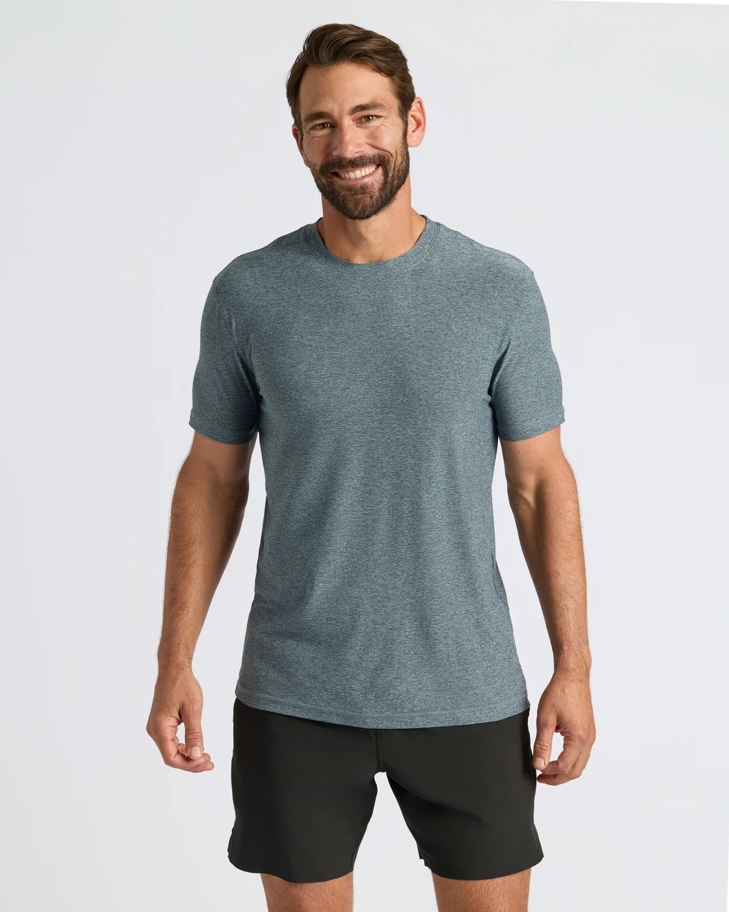 Man wearing a gray t-shirt and black shorts on a white background