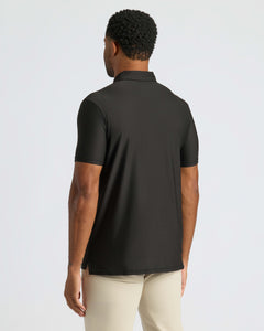 True ClassicBlack Active Polo 2.0 back view, paired with light-beige pants.