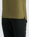 Military Green Active Polo 2.0 hem with side slit over black pants.