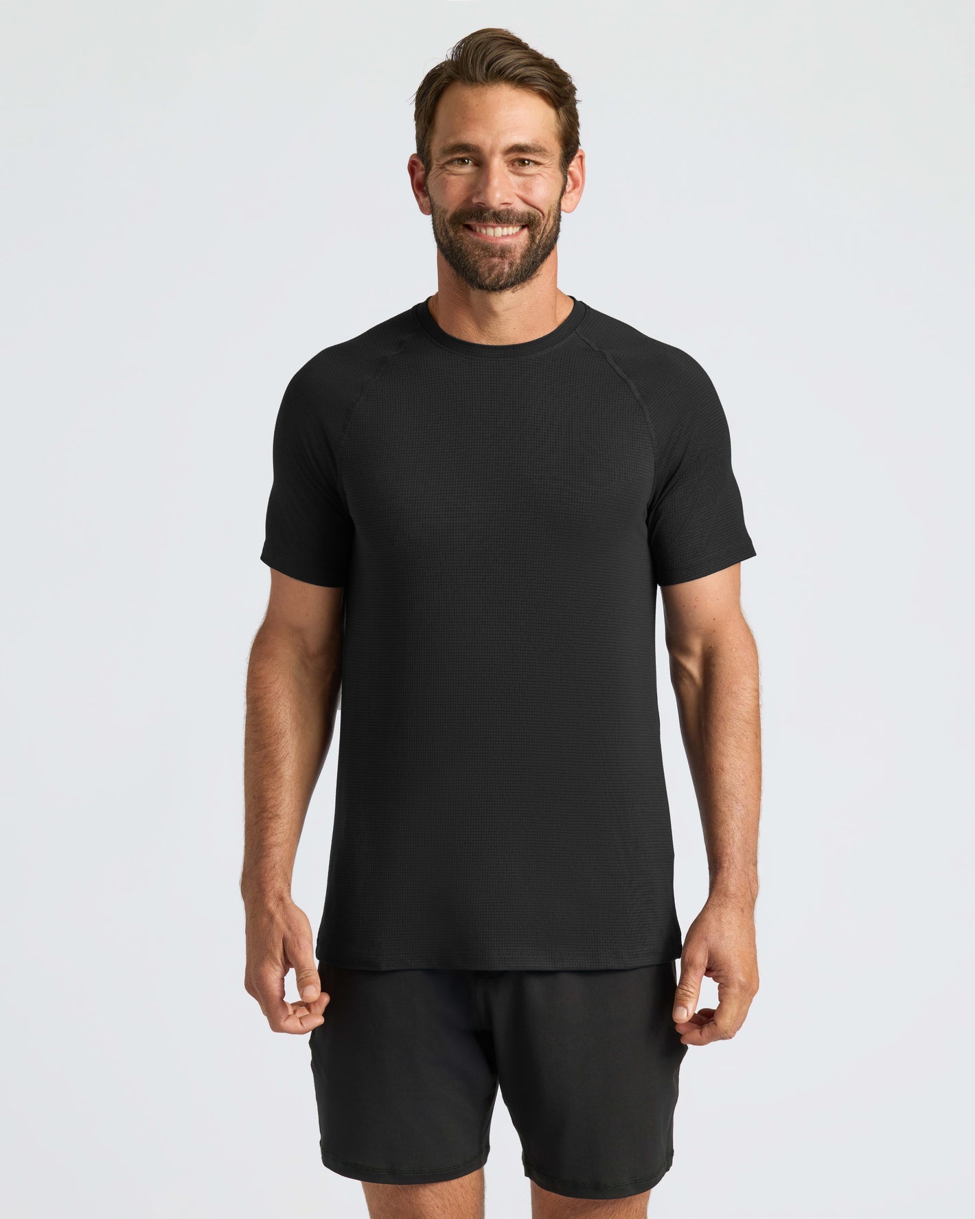 Man wearing Black Active Mesh Crew, stands relaxed, showcasing athletic fit.