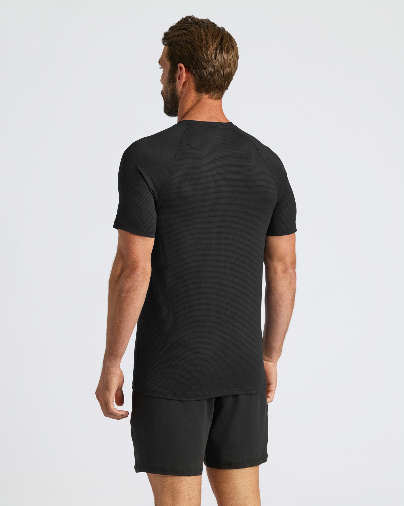 Man in Black Active Mesh Crew Tee and shorts, back view.