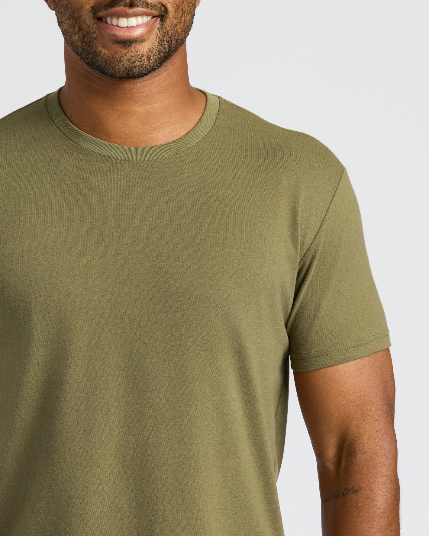 Man wearing Military Green Curved Hem Classic Crew Neck, showcasing its snug fit.