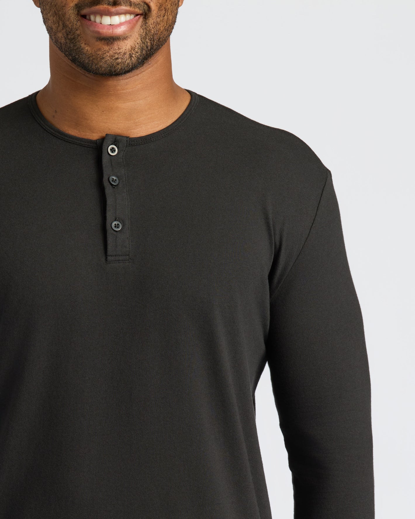 Person wearing All Black Classic Henley, showcasing neckline and button placket.