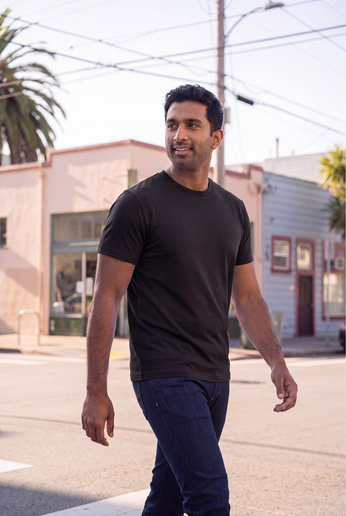 Everyday Standard - Heavy Crew, Jeans, & Boxers. Man wearing a black crew neck shirt and dark jeans while walking outdoors, showcasing men's basics.