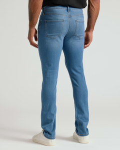 True ClassicMan wearing Medium Indigo Wash Slim Comfort Stretch Jeans shown from the back, paired with white sneakers and a black shirt, highlighting the slim fit and stretch fabric.