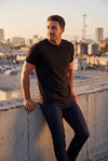 Pima Polish - Pima Crew, Jeans, & Boxers featuring a man in a black crew neck shirt and dark jeans on a rooftop, showcasing men's basics