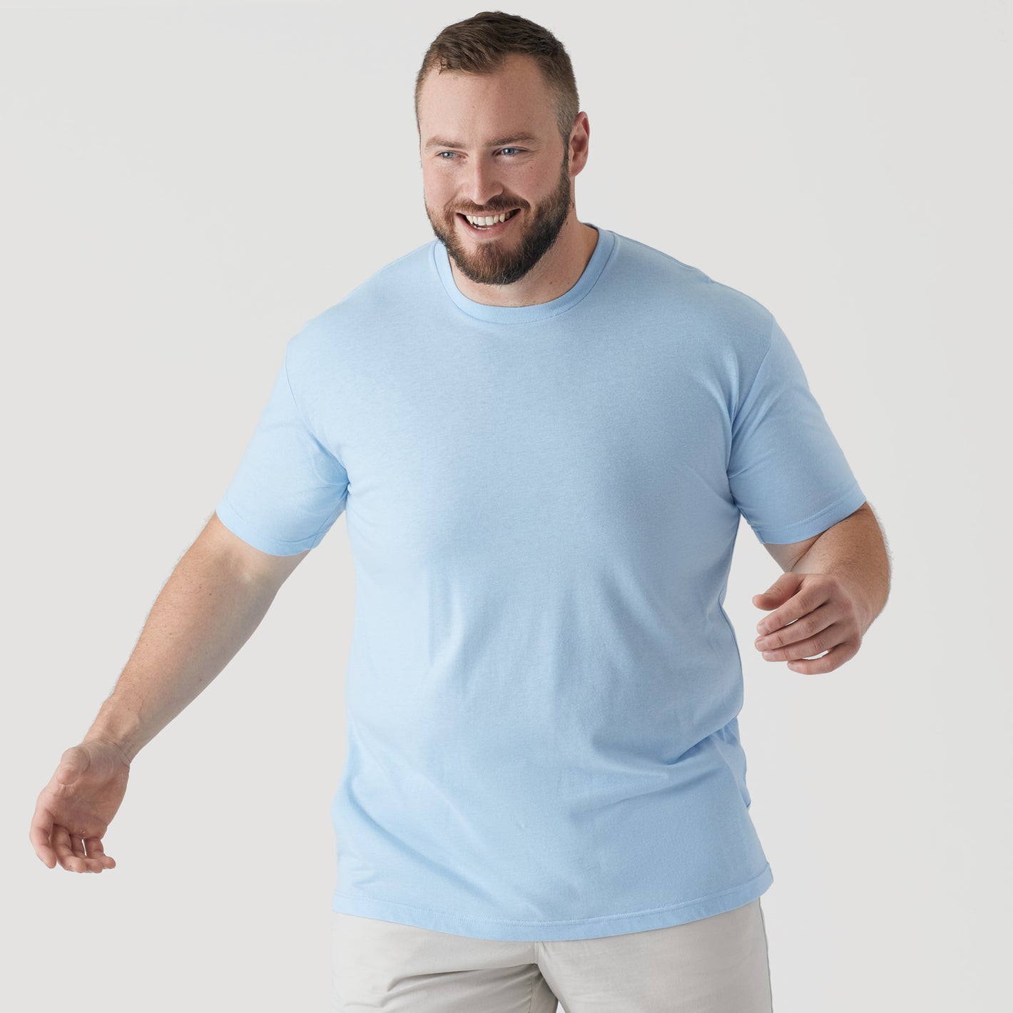 Man in Oxford Blue Short Sleeve Crew Neck Tee, smiling and stepping forward.