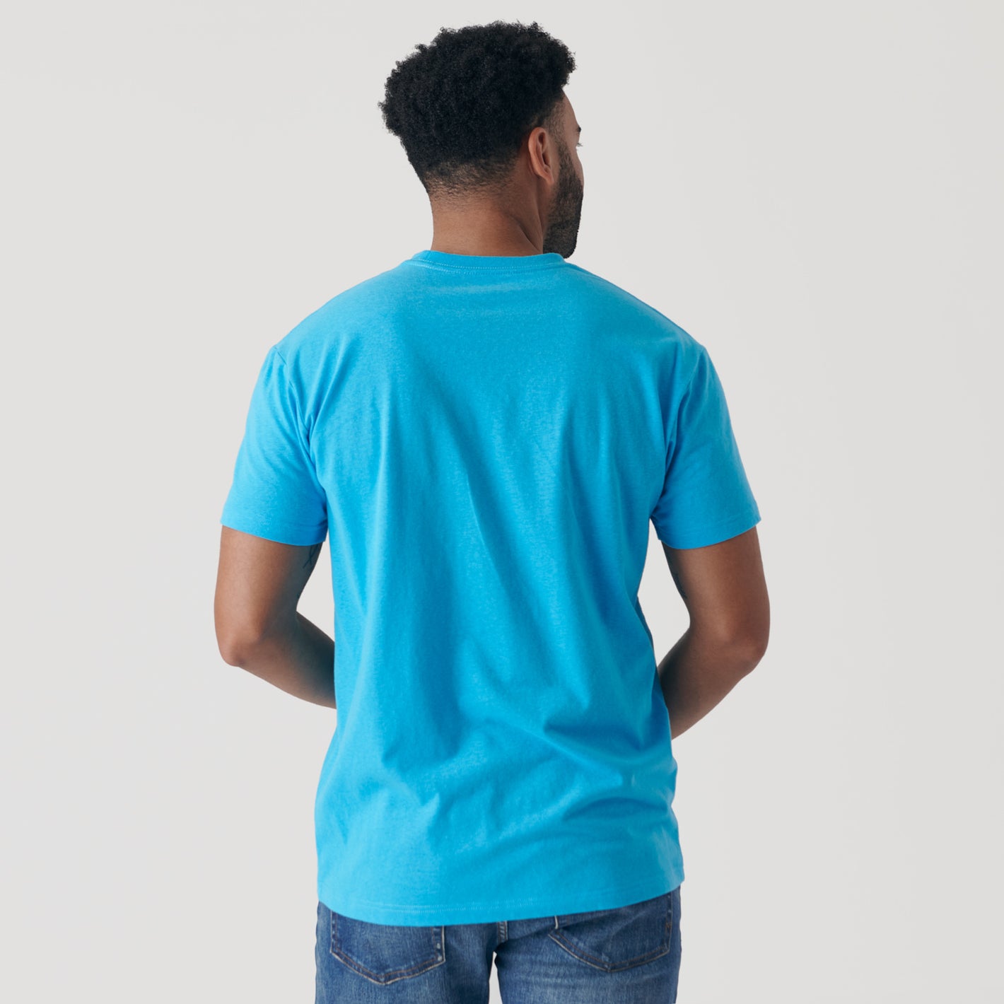 Man wearing Turquoise Short Sleeve Crew Neck Tee and blue jeans.