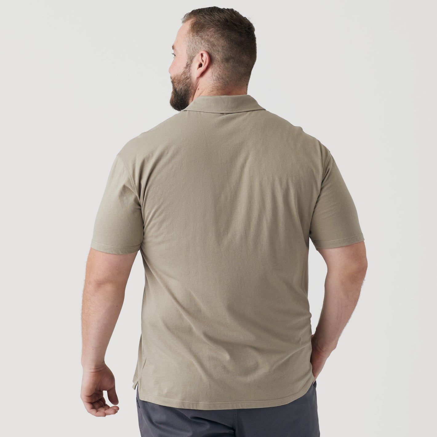 Man wearing Military Beige Short Sleeve Polo, back view, with dark shorts.