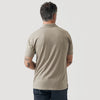 Man in Military Beige Short Sleeve Polo, tattoos on forearms, gray background.
