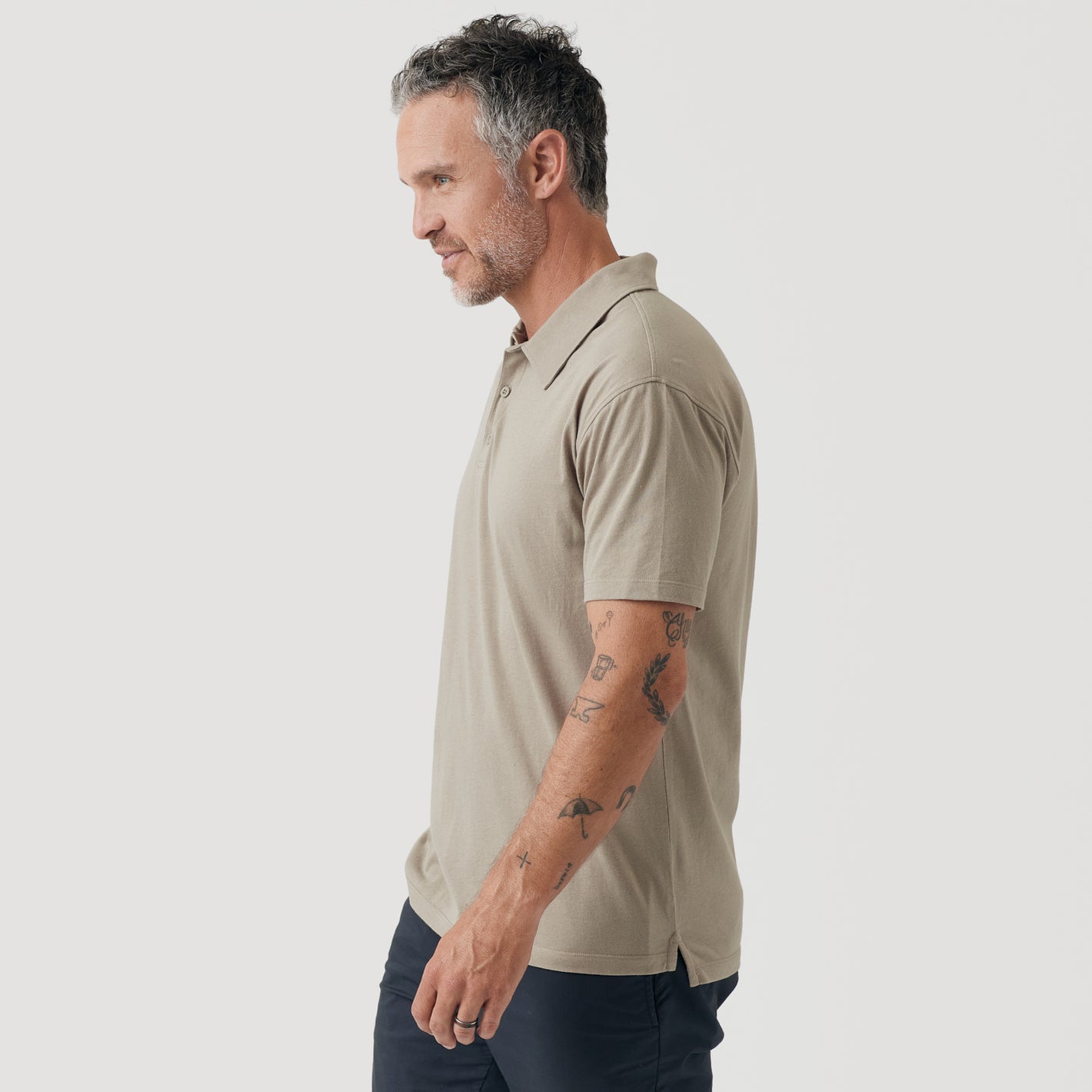 Man wearing Military Beige Short Sleeve Polo with tattoos visible on forearm.