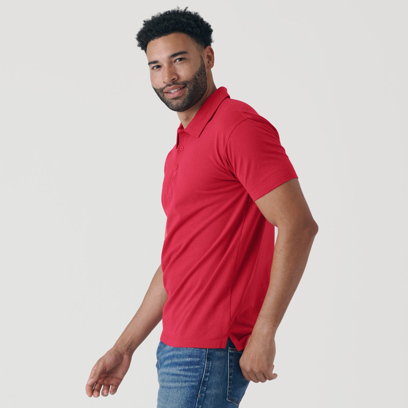 Man wearing Raspberry Classic Polo with jeans, smiling casually.