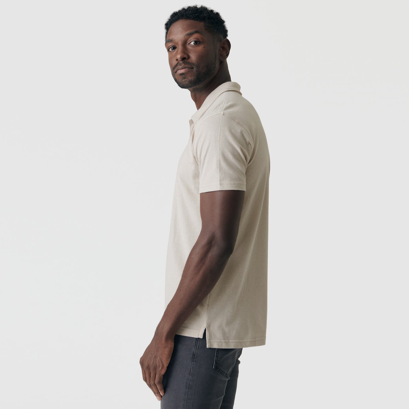 Young man wearing Sandstone Classic Polo in profile view.