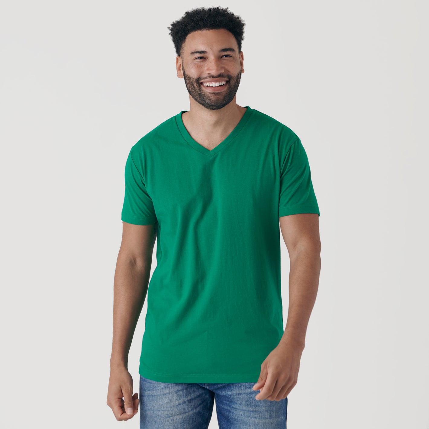 Man in Kelly Green V-Neck Tee and blue jeans smiling.
