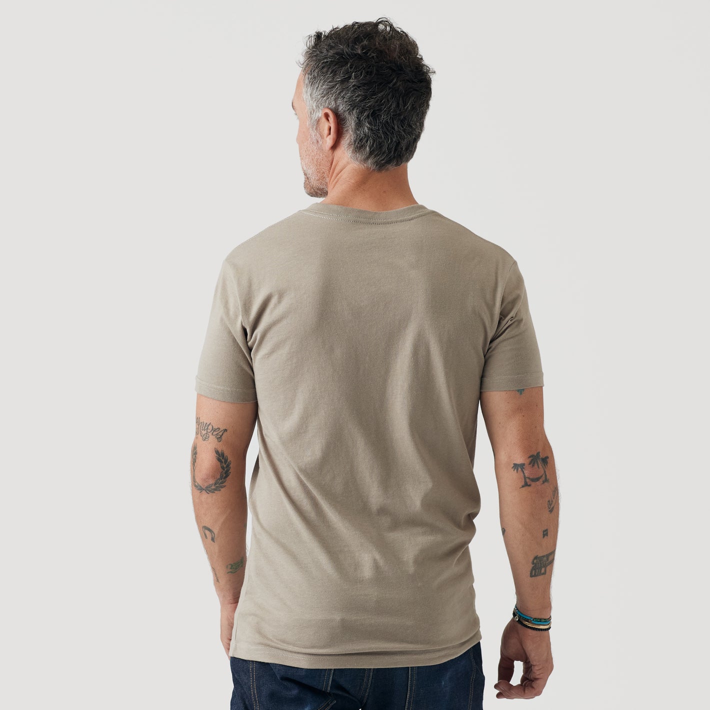 Man wearing Military Beige Classic V-Neck T-shirt, tattooed arms.