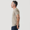 Man in Military Beige Classic V-Neck, dark jeans, tattoos visible.