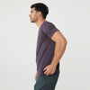 Man in Dark Purple V-Neck Tee, teal pants, profile view.