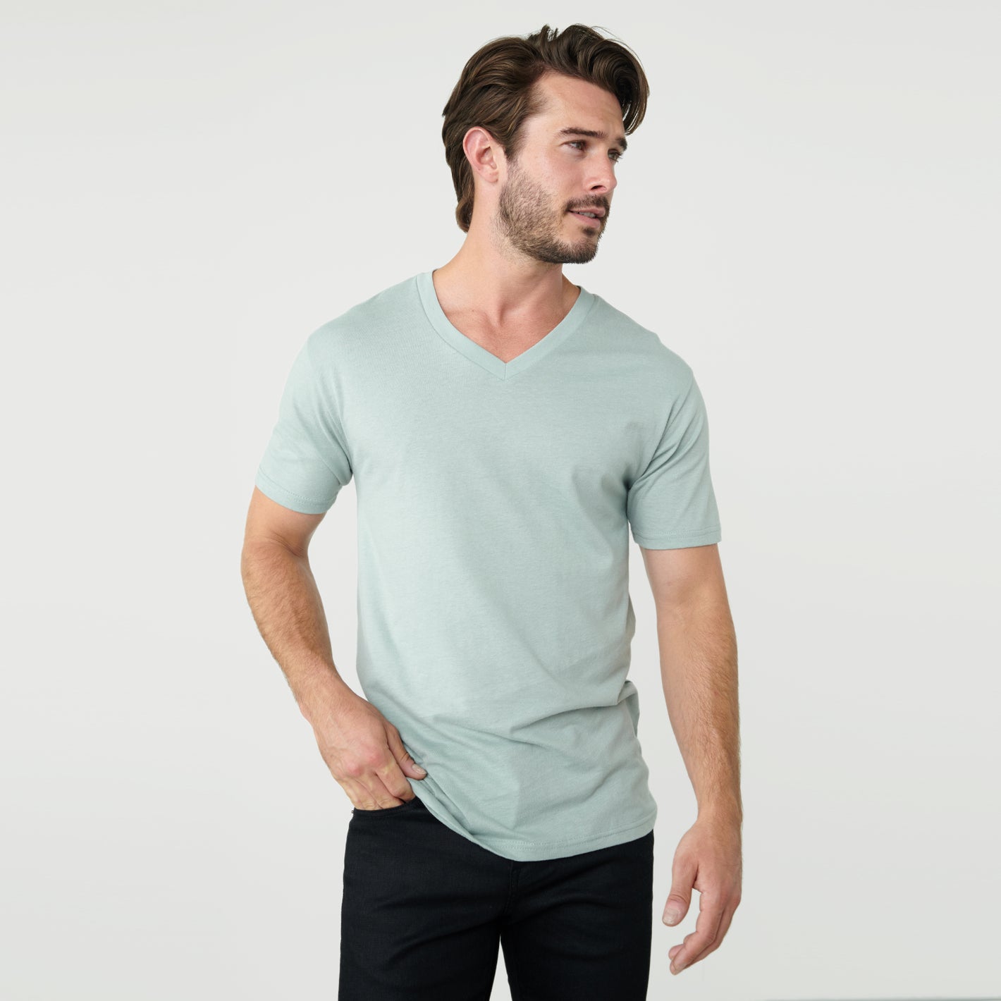 Man wearing Sage V-Neck Tee with dark pants, looking to the right.