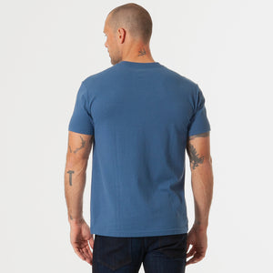 True ClassicMan wearing Stone Blue V-Neck Tee, tattoos visible, standing relaxed.