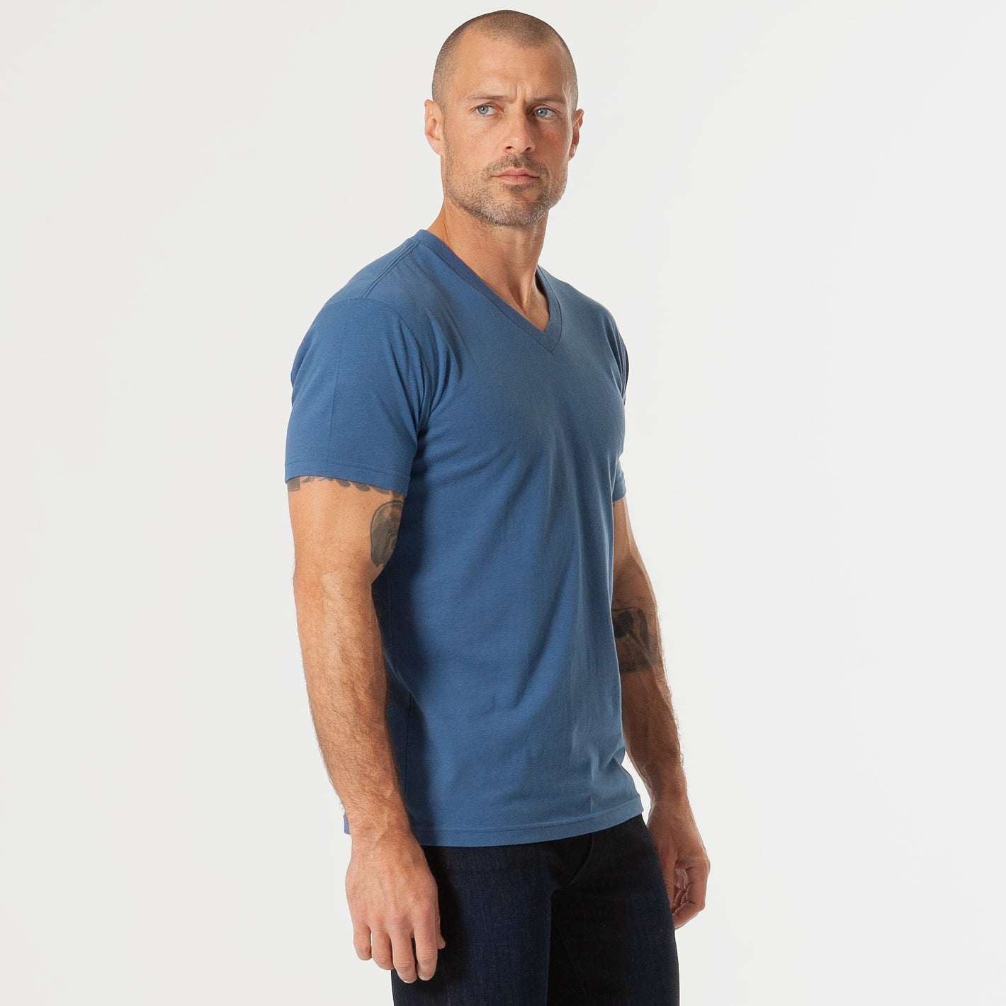 Man wearing Stone Blue V-Neck Tee and dark jeans.