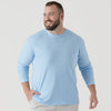 Man wearing Oxford Blue Long Sleeve Crew Neck Tee, smiling, hand in pocket.