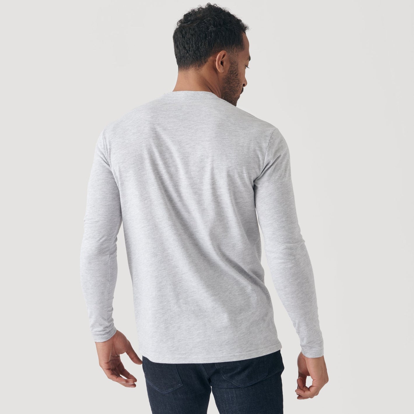 Man wearing Light Gray Long Sleeve Crew Neck Tee and dark jeans.