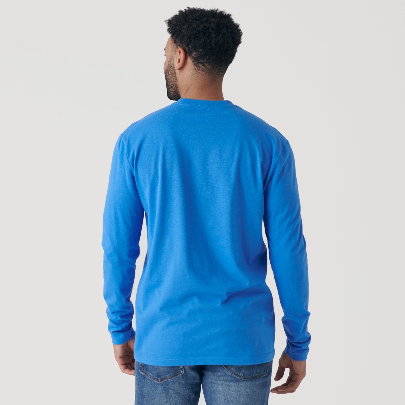 Man wearing Periwinkle Blue Long Sleeve Crew Neck Tee and blue jeans.