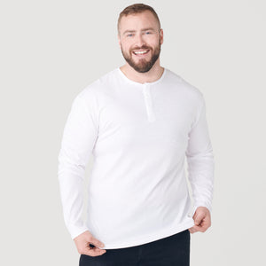 True ClassicMan wearing White Classic Long Sleeve Henley, smiling, and adjusting hem.
