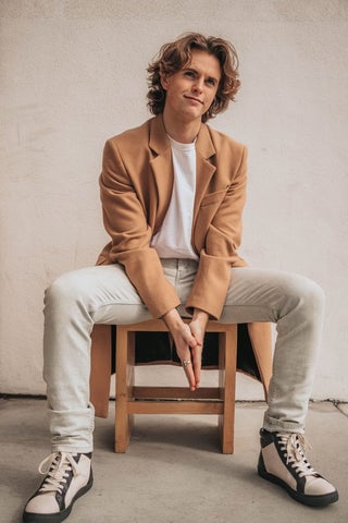 Model wearing a camel blazer with a white t-shirt underneath.