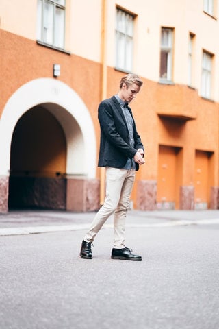 Model wearing a pair of khakis along with a dark sport coat, button-down, and dark shoes.