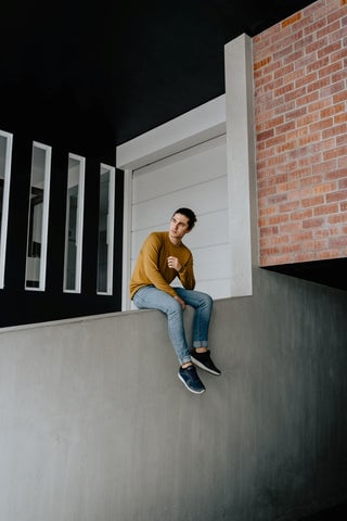 Model wearing a mustard-yellow long sleeve tee with a pair of jeans and dark sneakers.