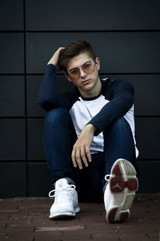 Model wearing a baseball tee with tailored denim pants and white sneakers.