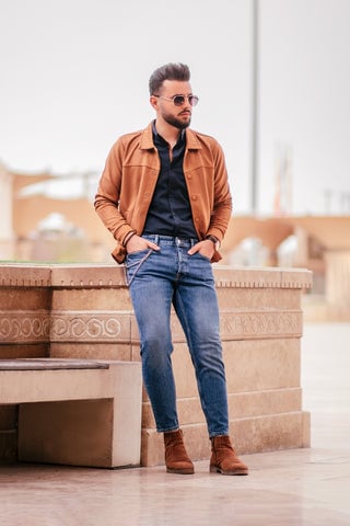Model wearing a light brown jacket with matching shoes along with a pair of jeans.