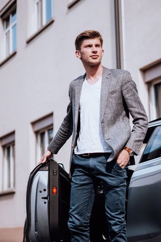 Model wearing a semi formal outfit featuring a light gray blazer and a white t-shirt tucked into a pair of jeans.