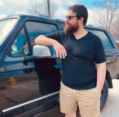 Bearded Man wearing A True Classic V-neck T-shirt leaning on his SUV