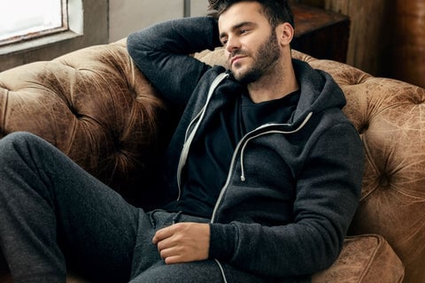 Man laying on the couch wearing a True Classic Carbon Fleece French Terry Zip Hoodie