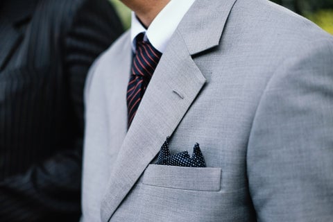 Close up of man wearing light gray suit with pocket square and tie